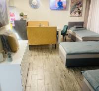 Wohnbereich in einem Einfamilienhaus mit Sofa, Sessel, Fernseher und Boden mit Holzdekor.