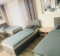 Drei Betten, zwei Nachttische und ein Boden mit Holzdekor in einem Einfamilienhaus.