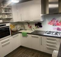 Küche in einem Einfamilienhaus mit weißen Schränken, dekorativen Fliesen und einem Boden mit Holzdekor.