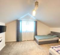 Schlafzimmer im Einfamilienhaus mit zwei Betten, Fernseher und Teppichboden.