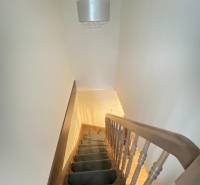 Eine Treppe mit Teppich führt nach oben, darüber hängt eine Leuchte in einem Einfamilienhaus.