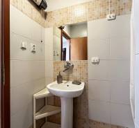 Badezimmer in einer Einzimmerwohnung mit Waschbecken, Spiegel und weißen Fliesen.