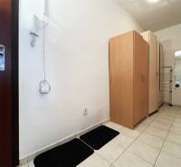 Flur in einer Einzimmerwohnung mit weißen Wänden, Fliesen und Schränken.