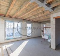 Der Innenraum eines im Bau befindlichen Gebäudes mit einer Holzdecke und großen Fenstern.