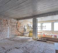 Baustelle in einem Gebäude mit Ziegelwänden und großen Fenstern. Der Bau befindet sich im Bauzustand.