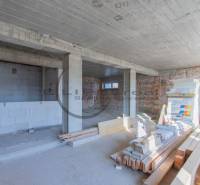 Innenraum eines im Bau befindlichen Gebäudes mit unebener Ziegelwand und Baumaterial auf dem Boden.