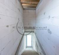 Ein Blick auf die Treppe in einem Gebäude mit Betonwänden und einem Fenster am Ende.