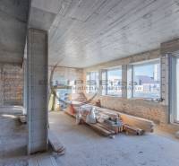 Innenraum eines Gebäudes mit Ziegelwänden, großen Fenstern und Baumaterial.