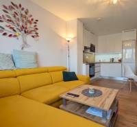 Helle Küche mit Holzboden und gelbem Sofa in einer 3-Zimmer-Wohnung.