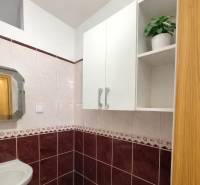 Badezimmer in einer 2-Zimmer-Wohnung mit Keramikfliesen und einem Spiegel über dem Waschbecken.