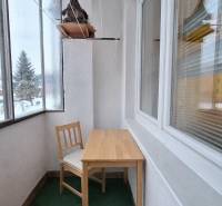 Veranda mit Glasfenstern mit einem Holztisch und einem Stuhl in einer 2-Zimmer-Wohnung.