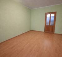 Ein leerer Raum mit Holzboden und grünen Wänden in einer Zweizimmerwohnung.