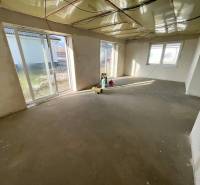 Ein geräumiger Raum in einem Einfamilienhaus mit rohem Betonboden, große Fenster bieten ausreichend Licht.