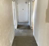 Der Flur eines Einfamilienhauses mit einer unbehandelten Decke und einem Betonboden.