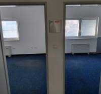 Innenraum von Büros mit blauem Teppichboden und Fenstern mit Jalousien.