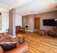 Wohnzimmer in einer Villa mit Holzboden, Ledersofa und Fernseher.