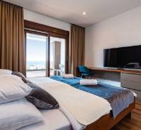 Schlafzimmer in der Villa mit Holzboden, Bett, Fernseher und Blick auf die Terrasse.