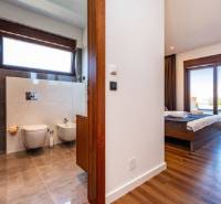 Innenraum der Villa mit Holzboden, Schlafzimmer und Badezimmer mit großem Fenster.