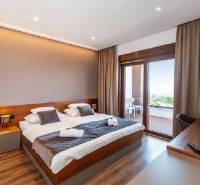 Luxuriöses Schlafzimmer in einer Villa mit Balkon, Holzboden, große Fenster.