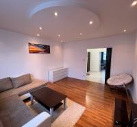 Wohnzimmer in einer 3-Zimmer-Wohnung mit einem bequemen Sofa und einem Boden in Holzoptik.