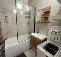 Badezimmer mit Badewanne, Schrank und Waschmaschine in einer 3-Zimmer-Wohnung.