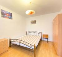 Schlafzimmer in einer 2-Zimmer-Wohnung mit Bett, Schrank und Boden in Holzoptik.