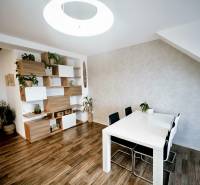 Esstisch, Stühle und Regale mit Dekorationselementen in einer 3-Zimmer-Wohnung mit Holzdekorboden.