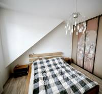 Schlafzimmer in einer 3-Zimmer-Wohnung mit Bett, Einbauschrank und Boden mit Holzdekor.