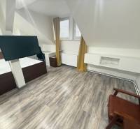 Ein Zimmer mit einem Boden in Holzoptik, einem modernen Fernseher und Möbeln in einer Einzimmerwohnung.