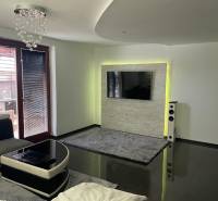 Wohnzimmer in einem Einfamilienhaus mit glänzendem Boden und Fernseher an der Wand.