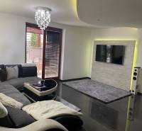 Wohnzimmer in einem Einfamilienhaus mit Sofa und Fernseher an der Wand mit Steinverkleidung.