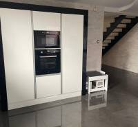 Die Küche in einem Einfamilienhaus mit glänzendem schwarzem Boden und weißen Geräten.