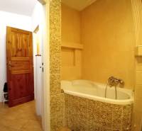 Ein Badezimmer in einem Einfamilienhaus mit einer mit Steinverkleidung ummantelten Badewanne und Holztüren.