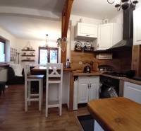 Küche und Wohnzimmer in einem Einfamilienhaus mit Holzboden und weißen Möbeln.