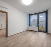 Ein Zimmer mit einem Holzboden, einem Fenster und einer Glastür in einer Zweizimmerwohnung.