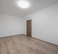 Ein leerer Raum mit Holzboden in einer Zweizimmerwohnung.