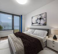 Schlafzimmer in einer 2-Zimmer-Wohnung mit einem bequemen Bett, einem Bild und einer Lampe auf dem Nachttisch.