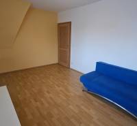 Wohnzimmer in einer 3-Zimmer-Wohnung mit Holzboden und blauem Sofa.