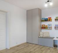 Kinderzimmer mit Holzboden, Wandschrank und Bücherregalen.