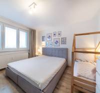 Schlafzimmer in einer 2-Zimmer-Wohnung mit Holzboden, großen Fenstern und einem Kinderbett.