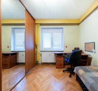 Ein Zimmer mit einem Holzboden, einem Tisch und einem Schrank in einer 3-Zimmer-Wohnung.