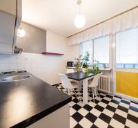 Küche in einer 3-Zimmer-Wohnung mit schwarz-weißen Fliesen, Esstisch und großen Fenstern.