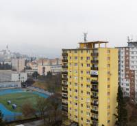 Blick auf Nitra von der Štúrová-Straße mit 3-Zimmer-Wohnungen, einem gelben Plattenbau und einem Sportplatz.