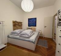 Schlafzimmer in einer 2-Zimmer-Wohnung mit Holzboden, Bett und weißem Schrank.