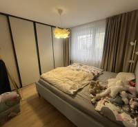 Schlafzimmer mit Bett, Einbauschrank, Vorhängen und Boden mit Holzdekor in einer 4-Zimmer-Wohnung.