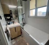 Badezimmer in einer 4-Zimmer-Wohnung mit Badewanne, Waschbecken, Spiegel und bunten Fliesen.