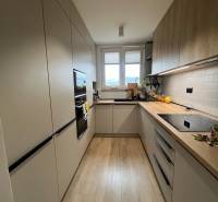 Küche in einer 4-Zimmer-Wohnung mit Holzboden, hellen Schränken, Fenster.