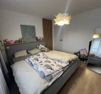 Schlafzimmer in einer 4-Zimmer-Wohnung mit einem komfortablen Bett und einem Boden mit Holzdekor.
