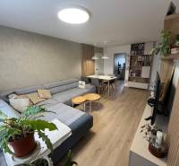 Wohnzimmer in einer Vierzimmerwohnung mit Ecksofa und Boden in Holzoptik.