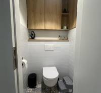 Badezimmer in einer 4-Zimmer-Wohnung mit farbigen Fliesen und Holzschränken an den Wänden.